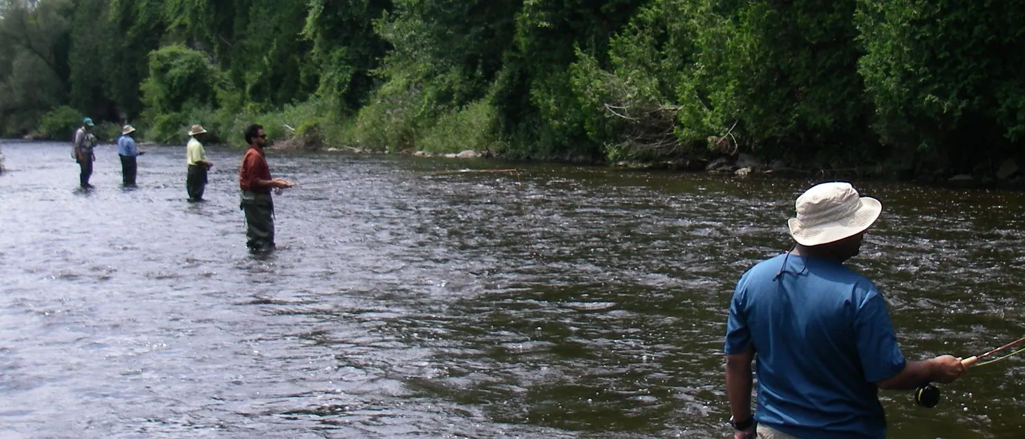 Anglers spread across a wide summer river during a guided session